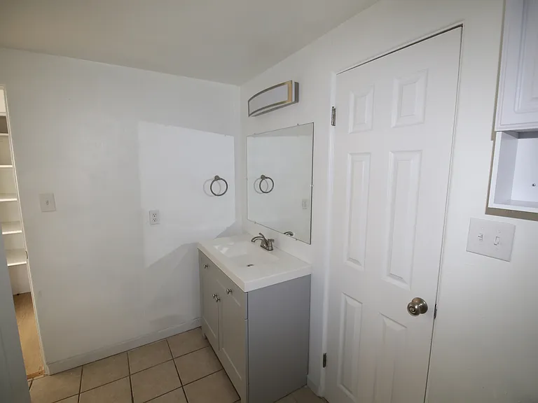 Bright and modern bathroom featuring a sleek vanity with a mirror, elegant fixtures, and a spacious white door.