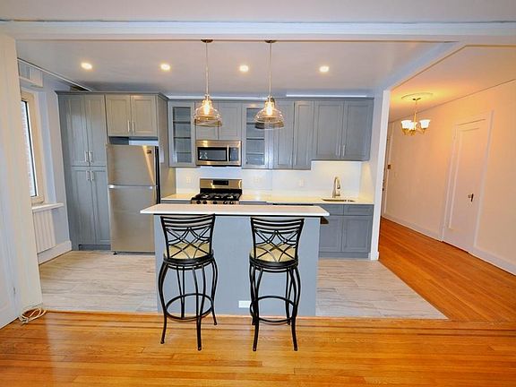 Renovated Kitchen with center Island, pendent lighting, Granite Counters, Stainless Steel Appliance including a dishwasher, range, microwave and refrigerator. The wall separating the eat-in-kitchen and living room have been removed and a center Island ins