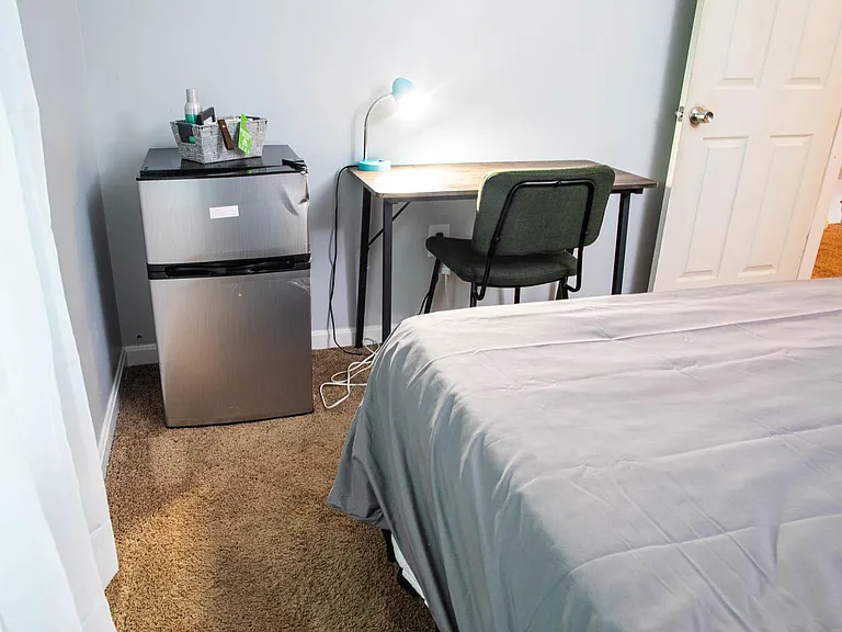 Bedroom includes a dedicated desk-and-chair workspace and an in-room mini fridge for added convenience.