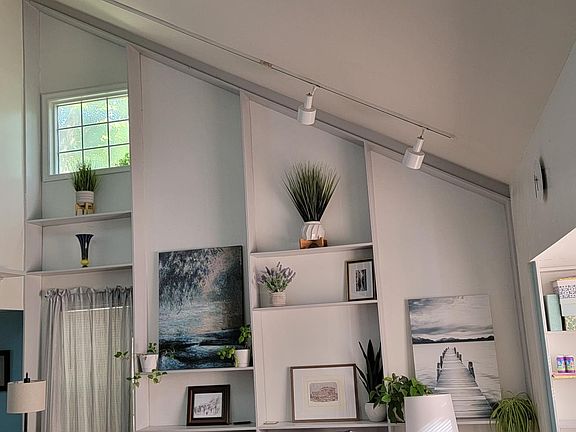 House's highlight is vaulted ceiling in spacious living room with built-in shelving, open to dining area.