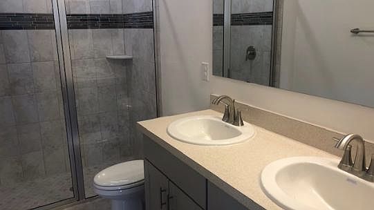 Large master bathroom with double vanity, tiled shower, and
