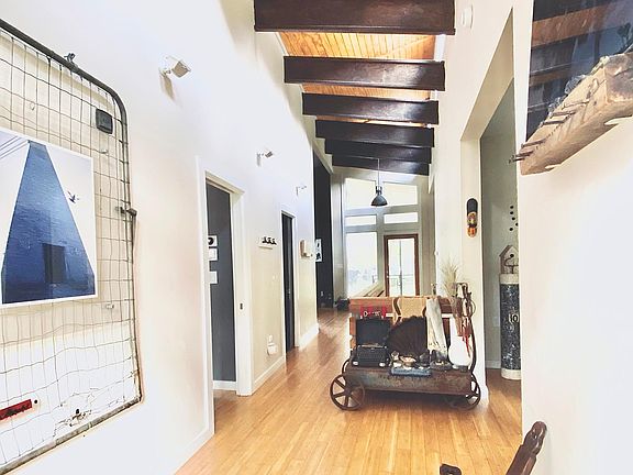 View from the front door. The primary suite is the first door on the left. On the right are the two bedrooms. Second door on the left is the second bathroom. The hallway opens into the open plan living, dining and kitchen at the end, which look out into t