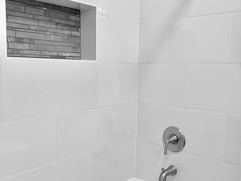 Deep soaking tub/shower with a tiled niche.