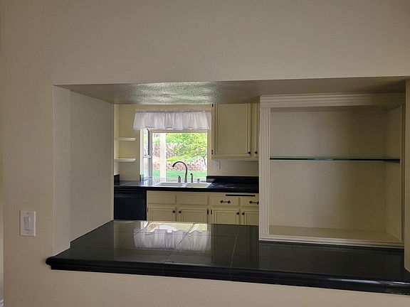 View into kitchen from dining room with custom display case including glass shelving.