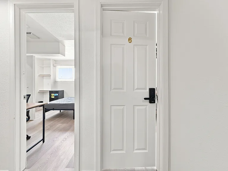 Private bedroom featuring light-toned flooring, a work desk area, and space for a full bed plus compact storage.