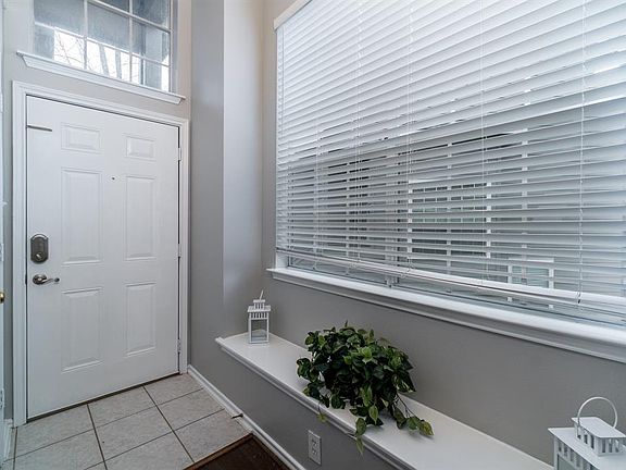 Entry has a window ledge, high ceiling, tile and a coat closet.
