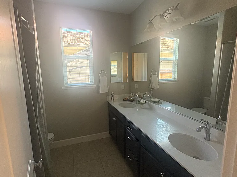 Full bathroom with dual sings and shower tub combo