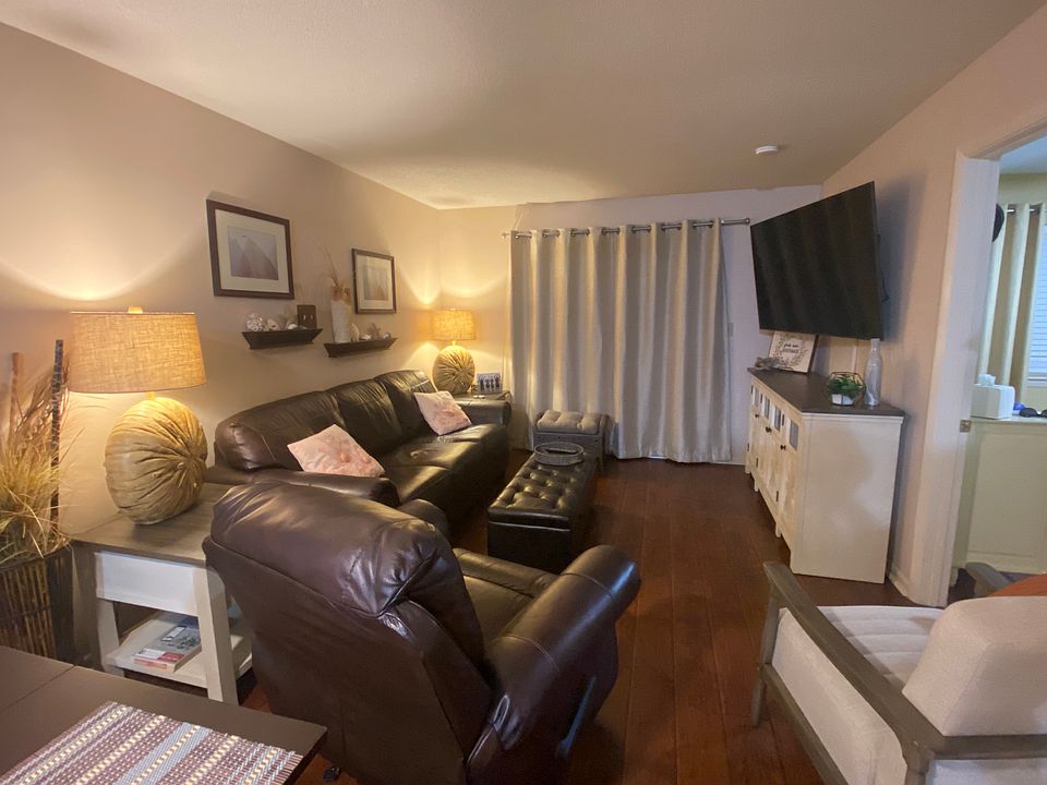 Living room with leather sofa sleeper, rocking recliner, club chair and 65" Smart TV with cable.