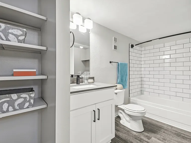 White tiled bathroom with white shelving and storage