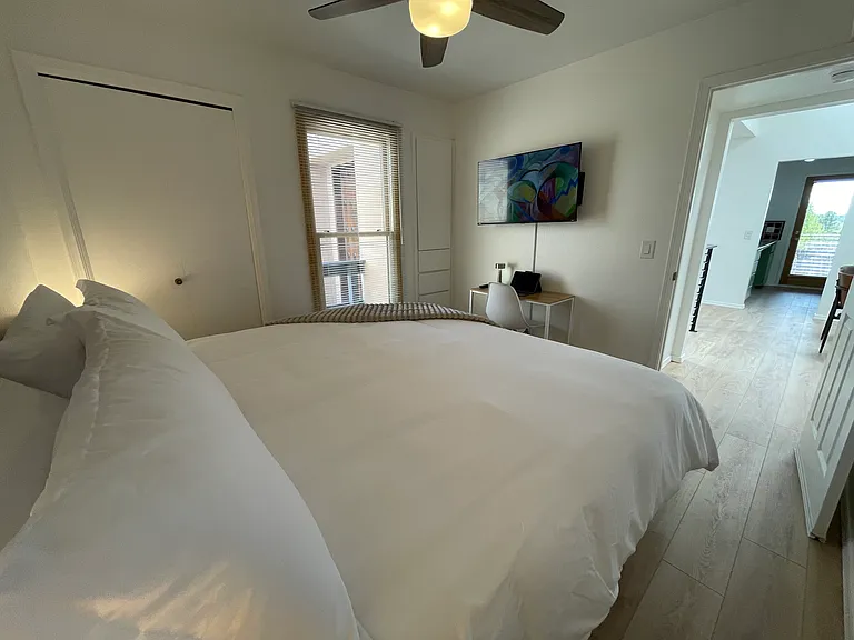 Upstairs Bedroom in king bed configuration and dedicated workspace, Roku TV, built-in storage, and closet