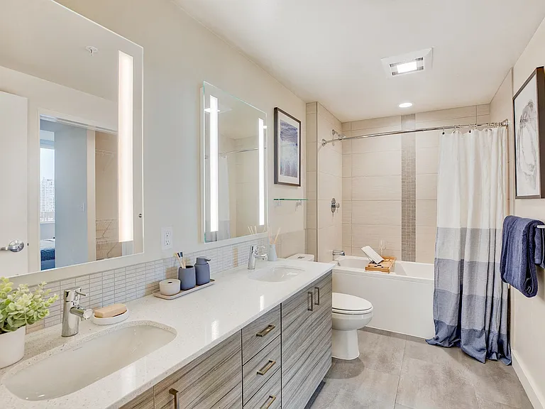 Bathroom boasting quartz countertops and tile backsplashes with tiled tub surrounds