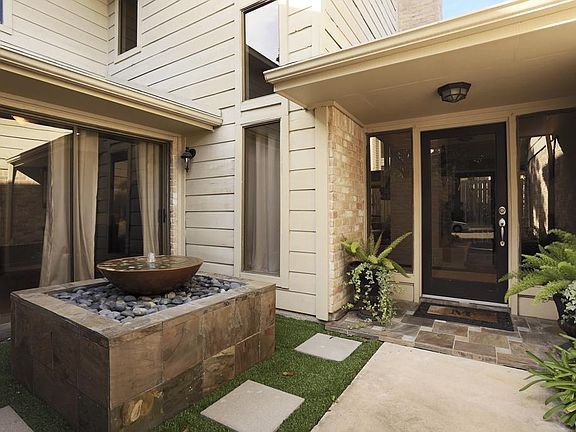 Gated entry features slate front porch with peaceful water feature and rich glass panel front doorway.