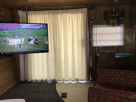 Front Patio Door with pull curtain. 55" LG HDTV, Small table and chairs for eating immediately right of the sliding door.