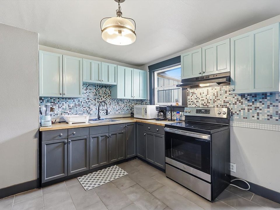 Updated kitchen with lots of light and ample storage space, butcher block counter, and retro tile backsplash.