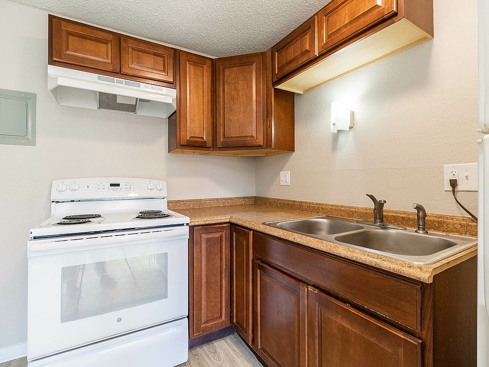 Charming kitchen with rich wooden cabinets, stainless steel sink, and a sleek white oven, perfect for culinary creativity.
