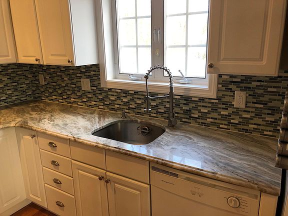 Spacious Kitchen area with custom granite counter tops and stainless steel sink/faucet. Able to look out to the outside