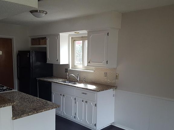 Kitchen with a pantry, gas stove, granite counters and beautiful tile backsplash.