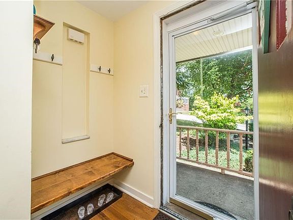 A full-view storm door fills the foyer with light. A built-in bench and wall hooks allow for easy shedding of shoes and coats. N