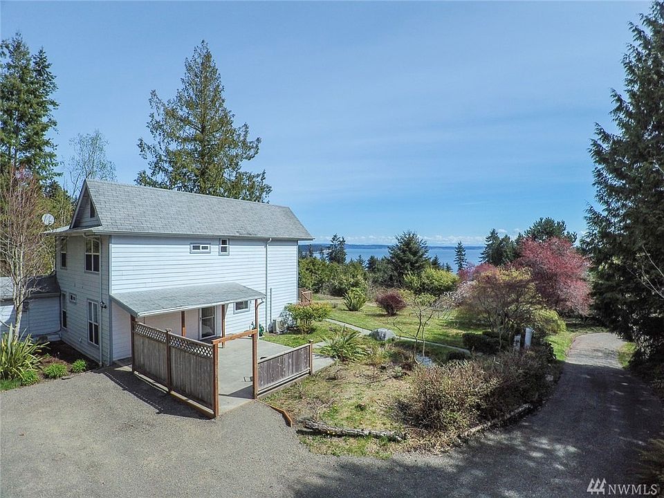 Driveway to the right for front door access part way up, or continue up to the back to bring supplies right into the kitchen. Small structure on the back of the house (far left) has furnace, water heater and electric panel. Beautiful deep rose-colored tree is on this property.
