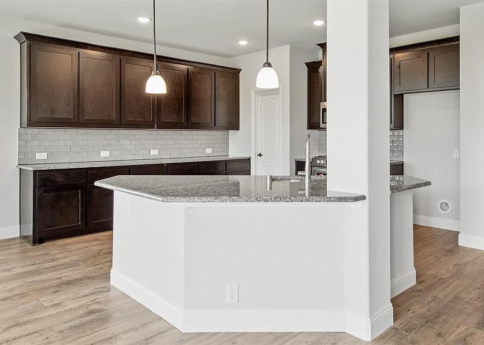 Kitchen featuring backsplash, light hardwood / wood-style floors, decorative light fixtures, and dark brown cabinetry
