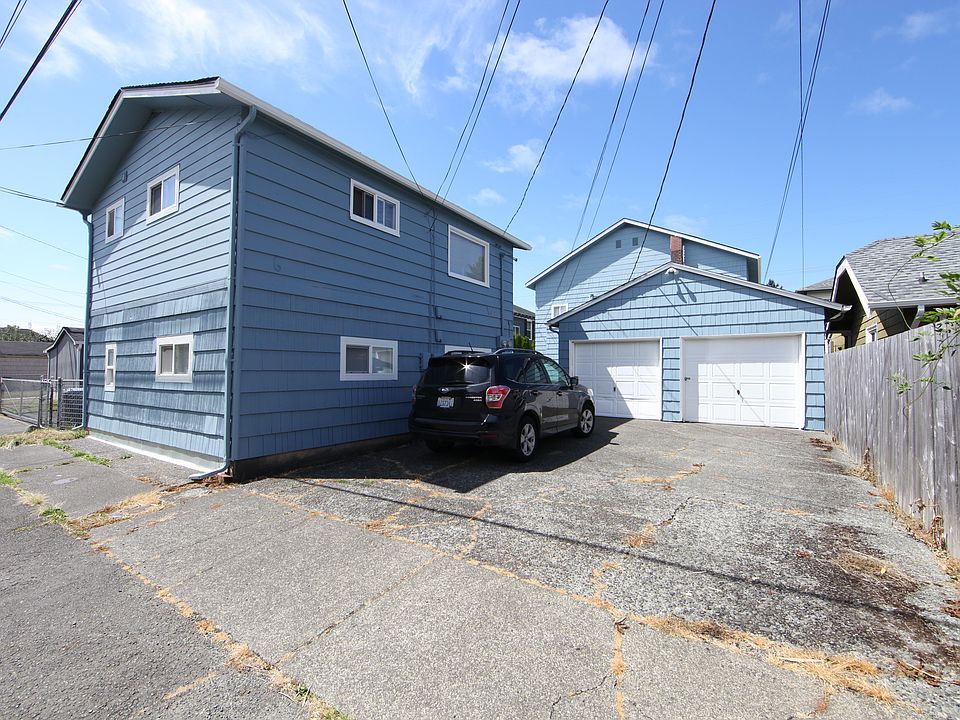 Wide angle view from the alley -- the duplex, parking spaces, and garages