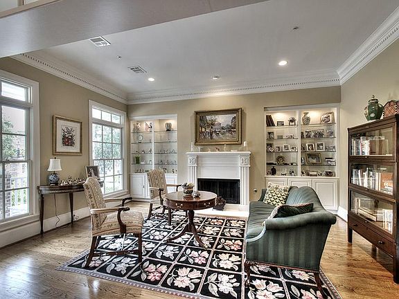 The formal living room overlooks the front porch & features lighted shelving and a fireplace.
