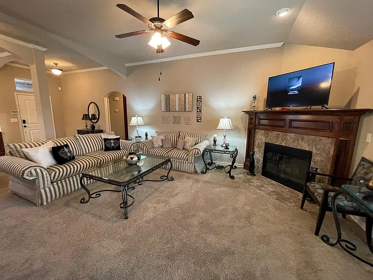 Sunny living room with ceiling fan and gas fireplace.