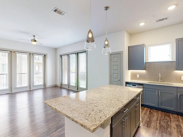 Apartment Kitchen with Stainless Steel Appliances, Dining and Living Room with Wood-Style Flooring and Patio/Balcony.