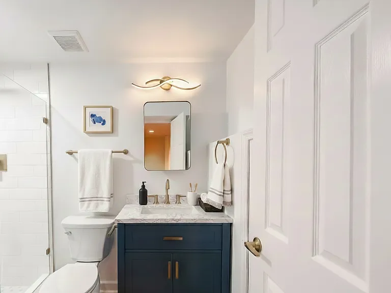 Bathroom view with updated vanity, toilet, towel storage, and modern finishes.