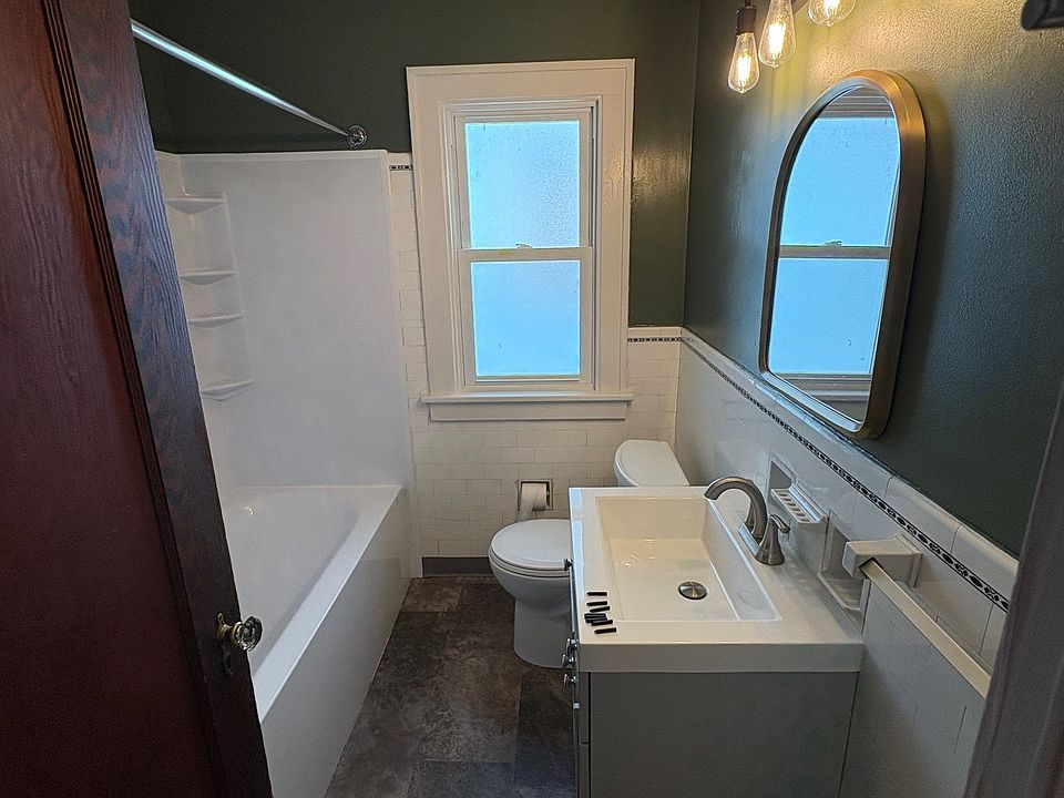 Bathroom with newer flooring, vanity, mirror and light. BathFitter tub.