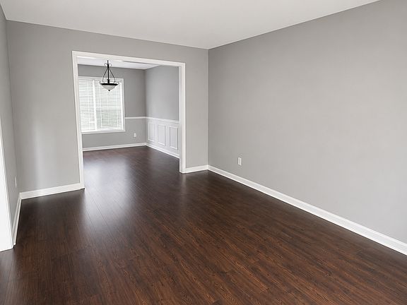 Bright, open living room featuring durable hardwood-style flooring, neutral paint, and a seamless flow into the dining area.