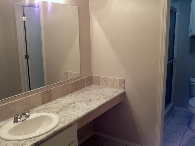 A DOOR SEPARATED THE SHOWER AREA FROM THE VANITY. BRIGHT VANITY LIGHTS WILL HAVE YOU LOOKING YOUR BEST FOR THE DAY.