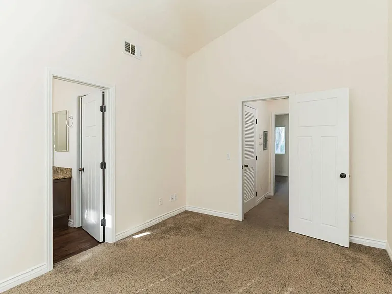 Carpeted bedroom with cathedral ceinling and bathroom at The Nines Townhomes in Escondido, California.