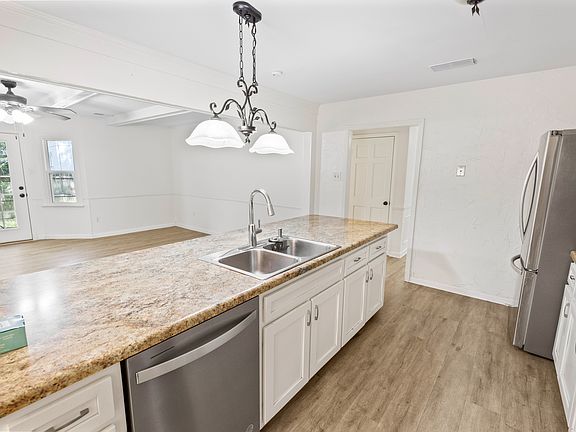 Bright and airy kitchen with granite island, stainless dishwasher, and seamless flow into the sun-lit living space.