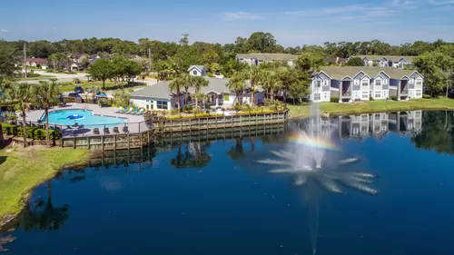 Experience the harmony of lakeside living at Indigo Isles, nestled amidst tranquil wooded areas, with stunning lake views and a large sundeck by the pool. - Indigo Isles