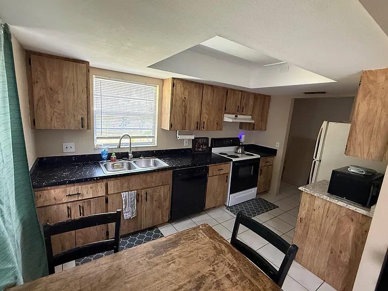 Functional kitchen with ample wood cabinetry, generous counters, double-basin sink, and full appliance set.