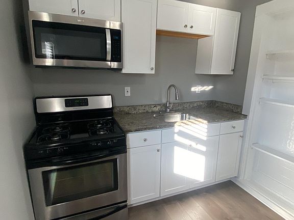 Renovated kitchen with stainless steel appliances, granite countertop, and new floors