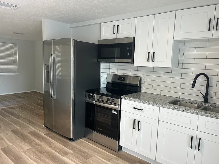 Newly updated bright kitchen with granite counter tops, new counter depth refrigerator with icemaker, new above the range microwave, and new glass top stove