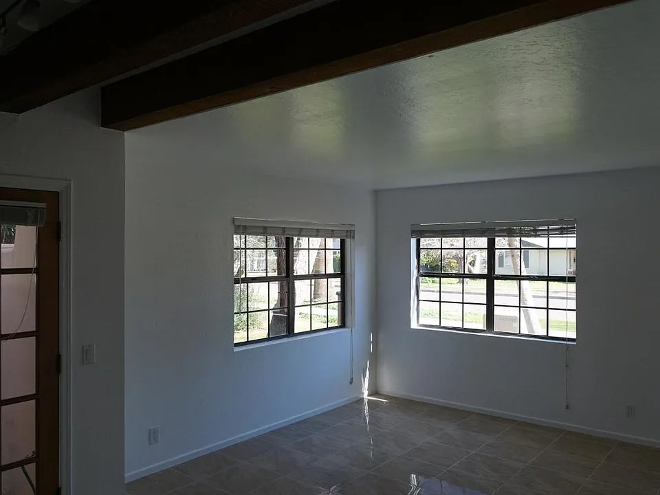 View of Living room with windows facing street. Coat closet and front door are to the right, just out of view.