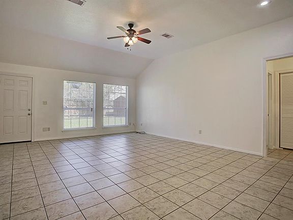 Large living room looks out to the backyard. High ceilings, ceiling fan and mini blinds are included.