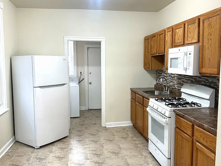 Eat-in kitchen with raised-panel oak cabinets, sandstone-style flooring & glass-bead backsplash