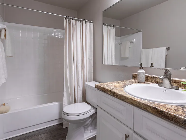 Our updated bathrooms feature a spacious vanity with granite-inspired countertops, brushed nickel fixtures, and a large mirror.