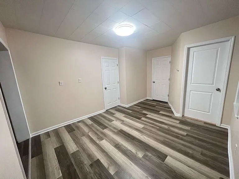 (Living room 1/3) Door on right is an exit, other 2 doors are bedrooms.