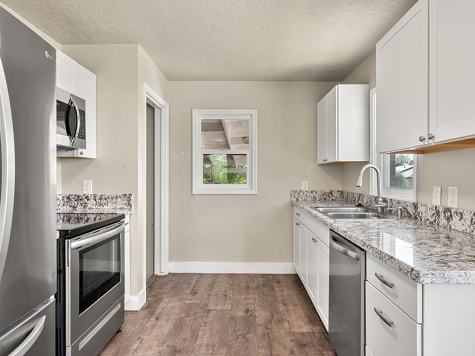 The heart of the home is the beautifully remodeled kitchen, featuring granite countertops, a spacious pantry, and abundant natural light that brightens the entire space. A large stainless-steel refrigerator with double doors and a pull-out freezer drawer 