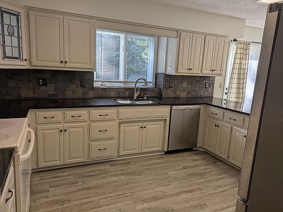 Sink area with window view and updated dishwasher.