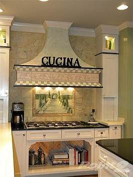 The custom range hood adds great flair to the kitchen.  The upper cabinets are the perfect place for display with lights and glass doors.  There are two appliance garages, hardwood floors, custom window treatments and a walk out to the lovely outdoor living space.