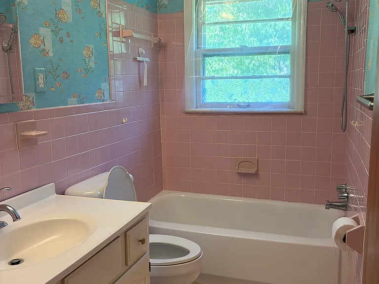 Bright full bathroom with tile flooring, a tub/shower combination, vanity cabinet, and natural light from the window.