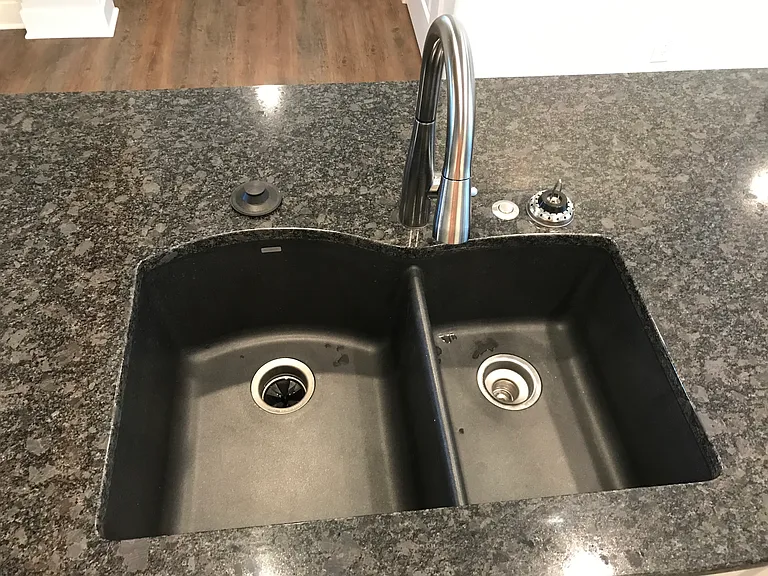 Black kitchen sink and brushed nickel faucets throughout place