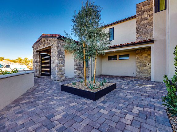 A well-designed outdoor patio area with a stone-clad building, a paved brick floor, and a potted tre