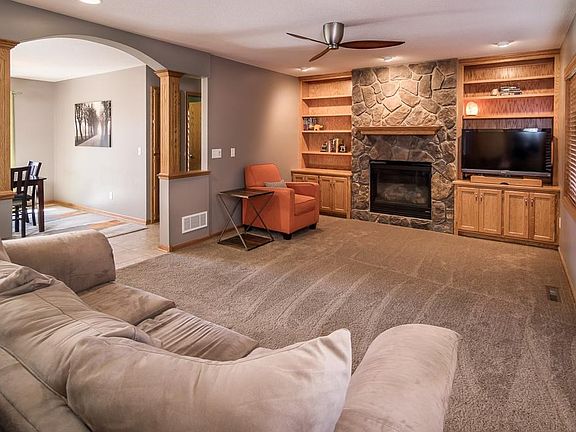 Spacious Living Room features a stone fireplace flanked with built-ins, recessed lighting and ceiling fan.  Oak pillars add architectural interest and polish to the room.